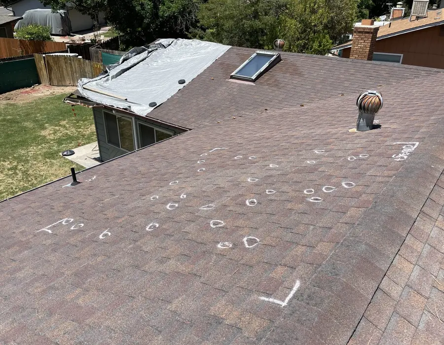 Chalk marks on a roof documenting hail hits for a claim