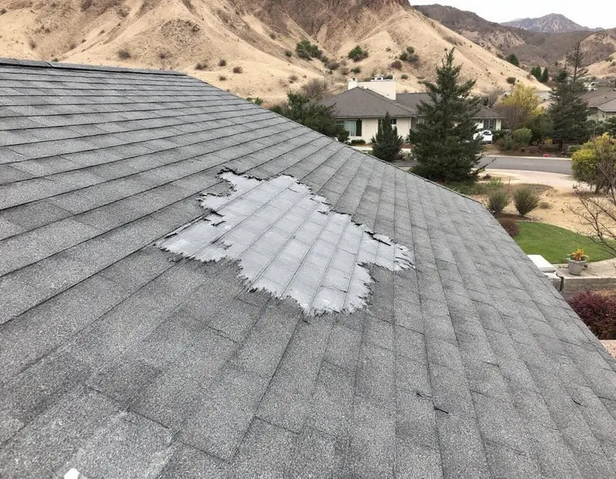 Shingles torn away by canyon wind on an east-slope Farmington roof, underlayment exposed