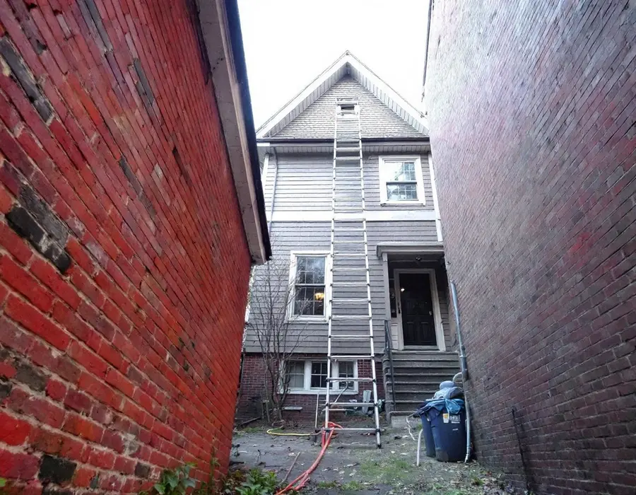 Ladder up a tall narrow house wedged between neighboring walls on a tight city lot