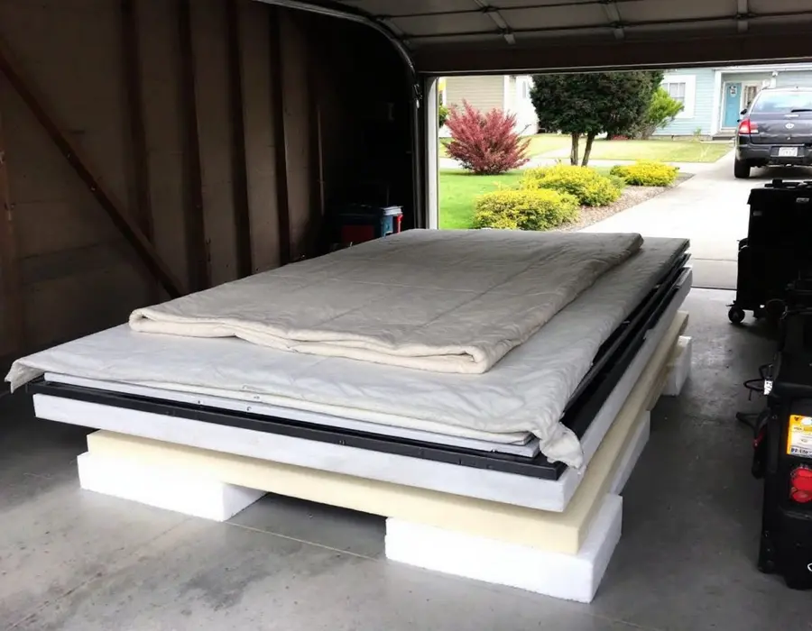 Solar panels stacked flat on foam blocks under a blanket in the homeowner's garage