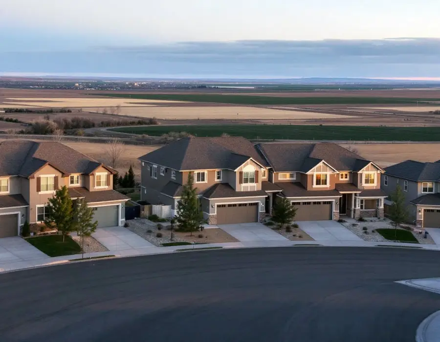 Street of 2000s subdivision homes in Syracuse with open ground toward the lake